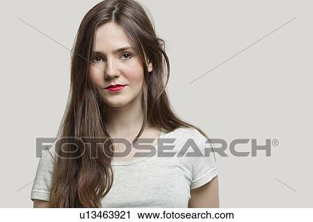 Stock Image - Portrait of serious young woman with red lips against gray background. Fotosearch