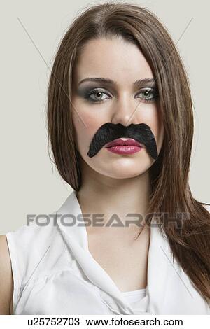 Portrait of serious young woman with fake mustache over gray background View Large Photo Image Stock Image - Portrait of serious young woman with fake mustache over gray background. Fotosearch