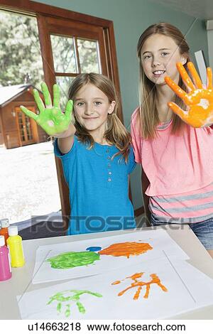 Portrait of sisters with paint covered hands and colorful handprints on papers View Large Photo Image Stock Photo - Portrait of sisters with paint covered hands and colorful handprints on papers. Fotosearch