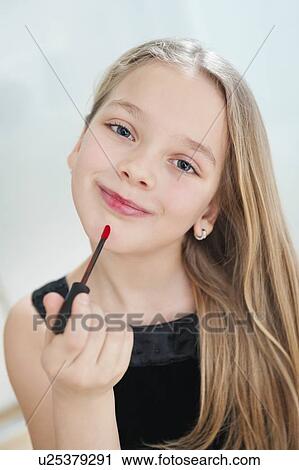 Portrait of young girl applying lipstick View Large Photo Image Stock Image - Portrait of young girl applying lipstick. Fotosearch