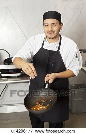 Stock Photo - Portrait of young male chef cooking food. Fotosearch