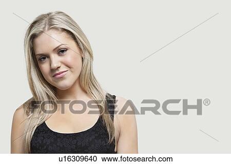 Stock Image - Portrait of young woman smiling over gray background. Fotosearch