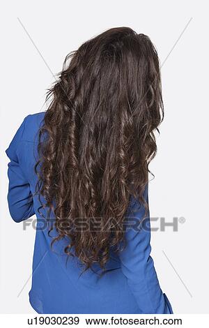 Stock Photo - Rear view of a young woman with long brunette hair over gray background. Fotosearch