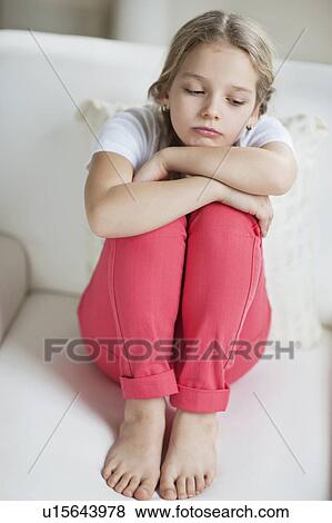 Stock Photo - Sad girl sitting on sofa. Fotosearch