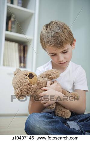 Stock Photograph - Sad young boy with his teddy bear. Fotosearch