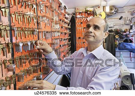 Stock Photography - Senior male locksmith working in key store. Fotosearch