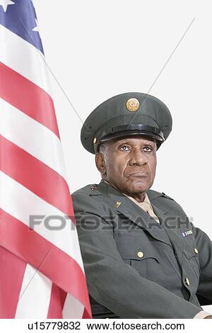 Senior male US military officer with American flag against gray background View Large Photo Image Stock Image - Senior male US military officer with American flag against gray background. Fotosearch