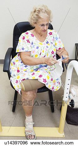 Stock Photograph - Senior woman with top half of prosthetic leg knitting. Fotosearch