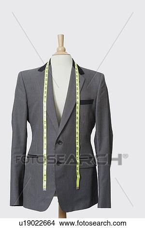 Picture - Suit on tailor's dummy with measuring tape over gray background. Fotosearch