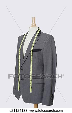 Stock Photo - Suit on tailor's dummy with measuring tape over gray background. Fotosearch