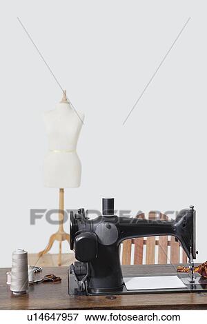 Stock Photo - Tailor's dummy and sewing machine with threads over gray background. Fotosearch