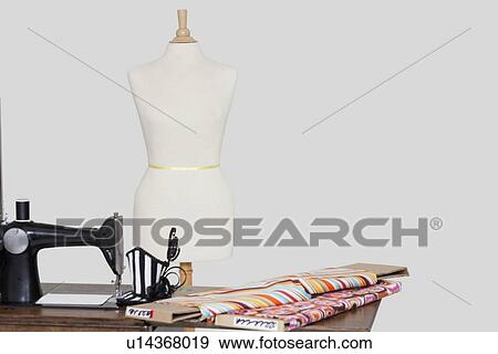 Stock Photo - Tailor's dummy with hat and cloth pattern on sewing machine over colored background. Fotosearch