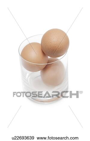 Stock Photo - Three brown eggs in drinking glass over white background. Fotosearch