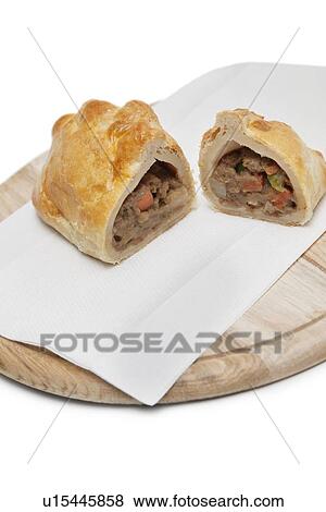 Stock Photo - Two pieces of Cornish pastry and tissue on wooden plate. Fotosearch