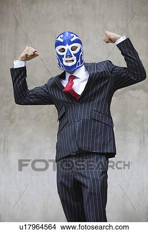 Young businessman flexing muscles in wrestling mask over gray background View Large Photo Image Picture - Young businessman flexing muscles in wrestling mask over gray background. Fotosearch