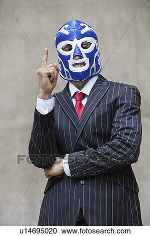 Young businessman in pinstripes suit and wrestling mask pointing up over gray background View Large Photo Image Stock Image - Young businessman in pinstripes suit and wrestling mask pointing up over gray background. Fotosearch