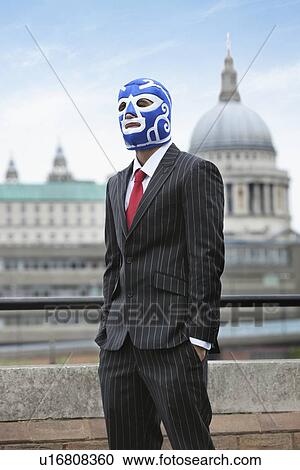 Stock Image - Young businessman wearing wrestling mask against St. Paul's Cathedral. Fotosearch