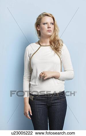 Young contemplative woman standing against light blue background View Large Photo Image Stock Image - Young contemplative woman standing against light blue background. Fotosearch