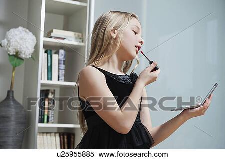 Stock Photography - Young girl applying lipstick at home. Fotosearch
