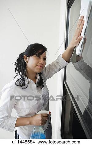 Picture - Young housemaid cleaning glass. Fotosearch