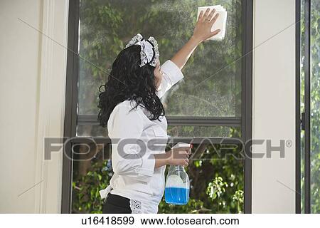 Stock Photo - Young housemaid cleaning window. Fotosearch