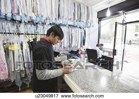 Young male employee and tailor working at dry cleaning shop View Large Photo Image Stock Photo - Young male employee and tailor working at dry cleaning shop. Fotosearch
