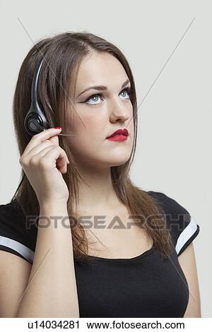 Young woman wearing headphones over gray background View Large Photo Image Stock Image - Young woman wearing headphones over gray background. Fotosearch