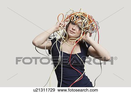 Stock Photo - Young woman with head tangled in colorful cables over gray background. Fotosearch