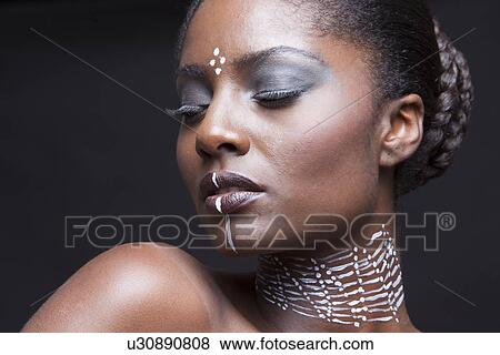 Stock Photo - Beautiful woman wearing tribal make-up paint closing eyes. Fotosearch
