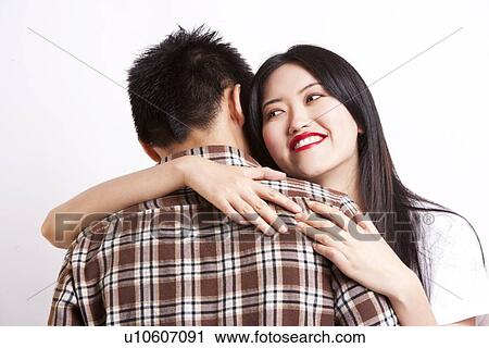 Beautiful young woman embracing man against white background View Large Photo Image Stock Image - Beautiful young woman embracing man against white background. Fotosearch