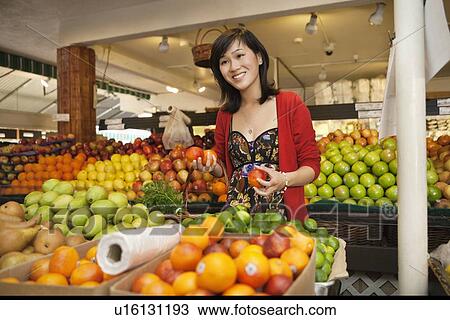 Beautiful young woman holding apple in farmer's market View Large Photo Image Stock Image - Beautiful young woman holding apple in farmer's market. Fotosearch