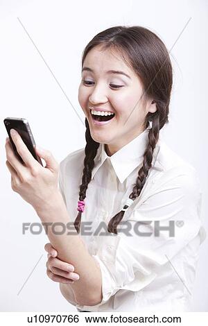 Cheerful young woman reading text message on her cell phone against white background View Large Photo Image Stock Photograph - Cheerful young woman reading text message on her cell phone against white background. Fotosearch