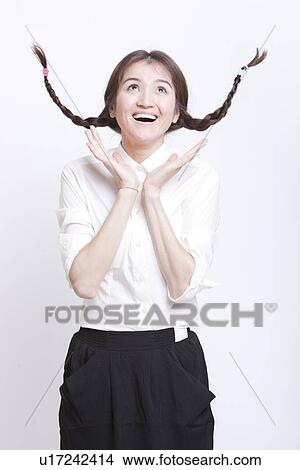 Cheerful young woman with braids curling upwards against white background View Large Photo Image Picture - Cheerful young woman with braids curling upwards against white background. Fotosearch