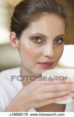 Close-up portrait of a young woman holding coffee cup View Large Photo Image Stock Photograph - Close-up portrait of a young woman holding coffee cup. Fotosearch