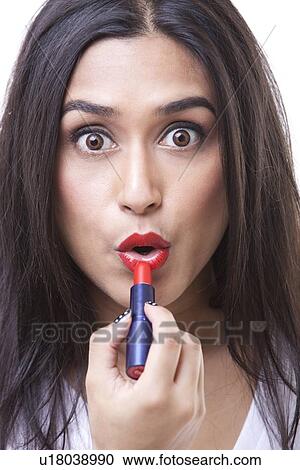 Close-up portrait of young woman applying lipstick and pouting over white background View Large Photo Image Stock Image - Close-up portrait of young woman applying lipstick and pouting over white background. Fotosearch