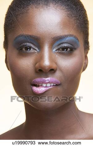 Close-up view of beautiful woman wearing make-up biting lip View Large Photo Image Stock Image - Close-up view of beautiful woman wearing make-up biting lip. Fotosearch