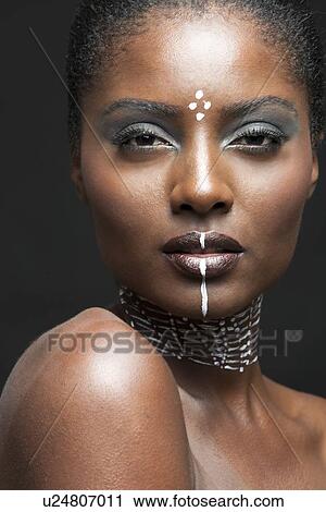 Stock Image - Close-up view of beautiful woman wearing tribal make-up paint. Fotosearch