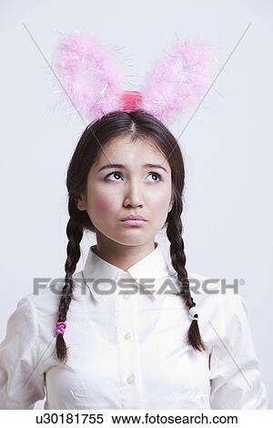 Contemplative Asian woman with bunny ears against white background View Large Photo Image Stock Photography - Contemplative Asian woman with bunny ears against white background. Fotosearch