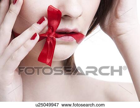 Cropped view of young woman with red ribbon tied over mouth against white background View Large Photo Image Stock Photo - Cropped view of young woman with red ribbon tied over mouth against white background. Fotosearch