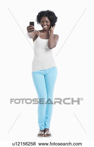 Happy young African American woman taking self portrait over white background View Large Photo Image Stock Photo - Happy young African American woman taking self portrait over white background. Fotosearch
