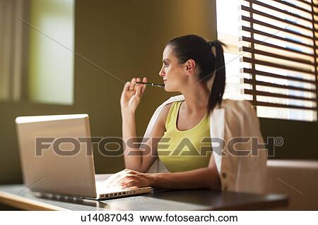 Happy young woman sitting at desk with laptop View Large Photo Image Stock Image - Happy young woman sitting at desk with laptop. Fotosearch