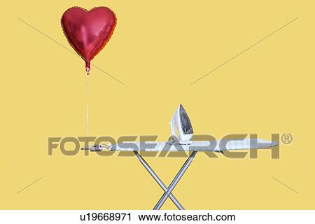 Heart shaped balloon tied to ironing board over yellow background View Large Photo Image Stock Image - Heart shaped balloon tied to ironing board over yellow background. Fotosearch