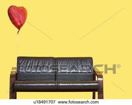 Heart shaped balloon tied to sofa over yellow background View Large Photo Image Stock Photo - Heart shaped balloon tied to sofa over yellow background. Fotosearch