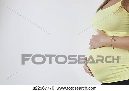 Midsection of young pregnant woman against white background View Large Photo Image Stock Image - Midsection of young pregnant woman against white background. Fotosearch