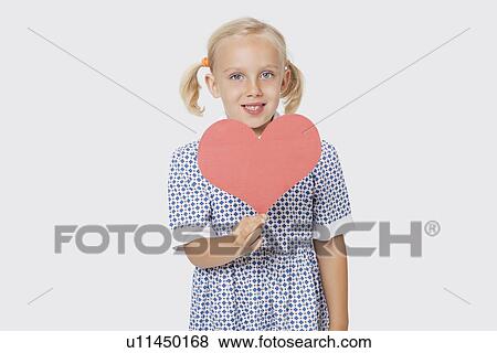 Portrait of a happy young girl holding pink paper heart over white background View Large Photo Image Stock Photo - Portrait of a happy young girl holding pink paper heart over white background. Fotosearch