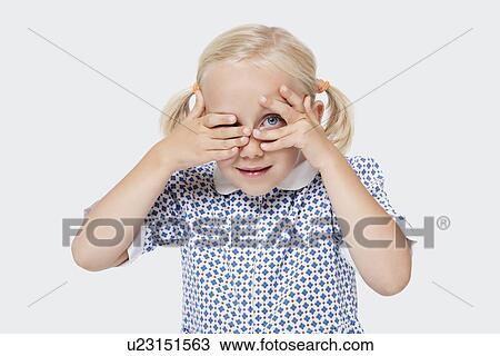 Portrait of a young girl peeking through fingers over white background View Large Photo Image Stock Image - Portrait of a young girl peeking through fingers over white background. Fotosearch