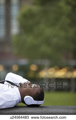 Portrait of Afircan American businessman lying down listening to music in the park View Large Photo Image Stock Image - Portrait of Afircan American businessman lying down listening to music in the park. Fotosearch