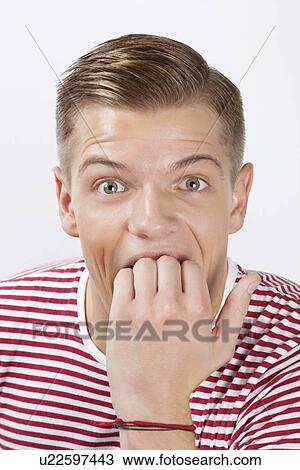 Portrait of amazed young man biting his finger over white background View Large Photo Image Stock Image - Portrait of amazed young man biting his finger over white background. Fotosearch