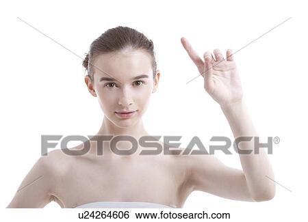 Stock Photograph - Portrait of beautiful young woman pointing up against white background. Fotosearch