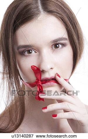 Portrait of beautiful young woman with red ribbon tied over mouth against white background View Large Photo Image Stock Photo - Portrait of beautiful young woman with red ribbon tied over mouth against white background. Fotosearch